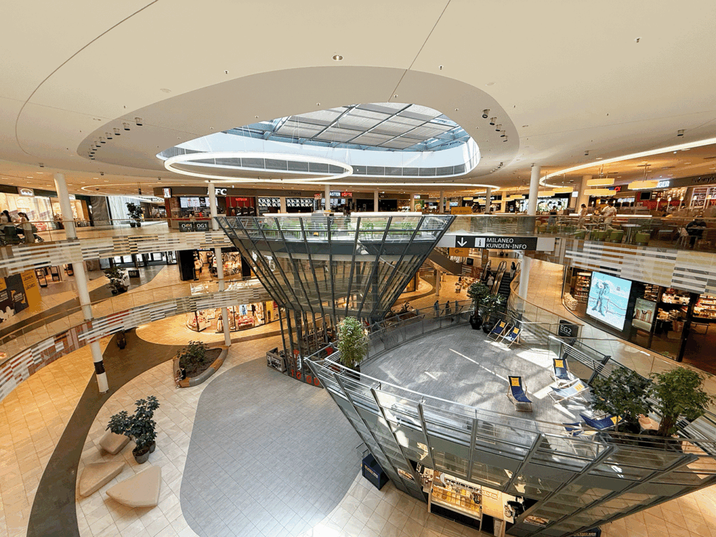 Innenaufnahme des Einkaufszentrums Milaneo mit Restaurants, Shops und Aufenthaltsbereichen.