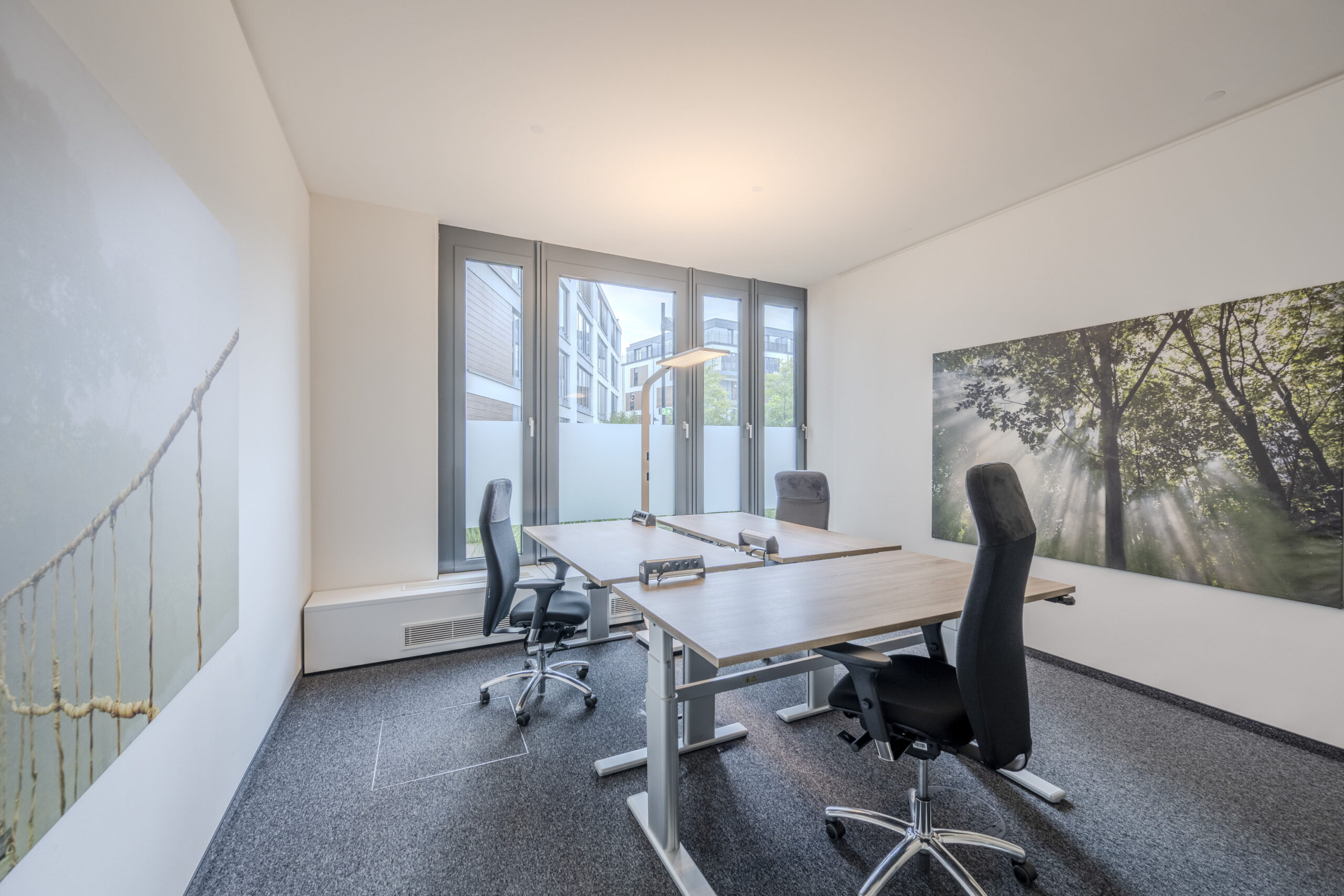 Modernes Büro mit zwei Arbeitsplätzen und großflächigen Wandbildern.