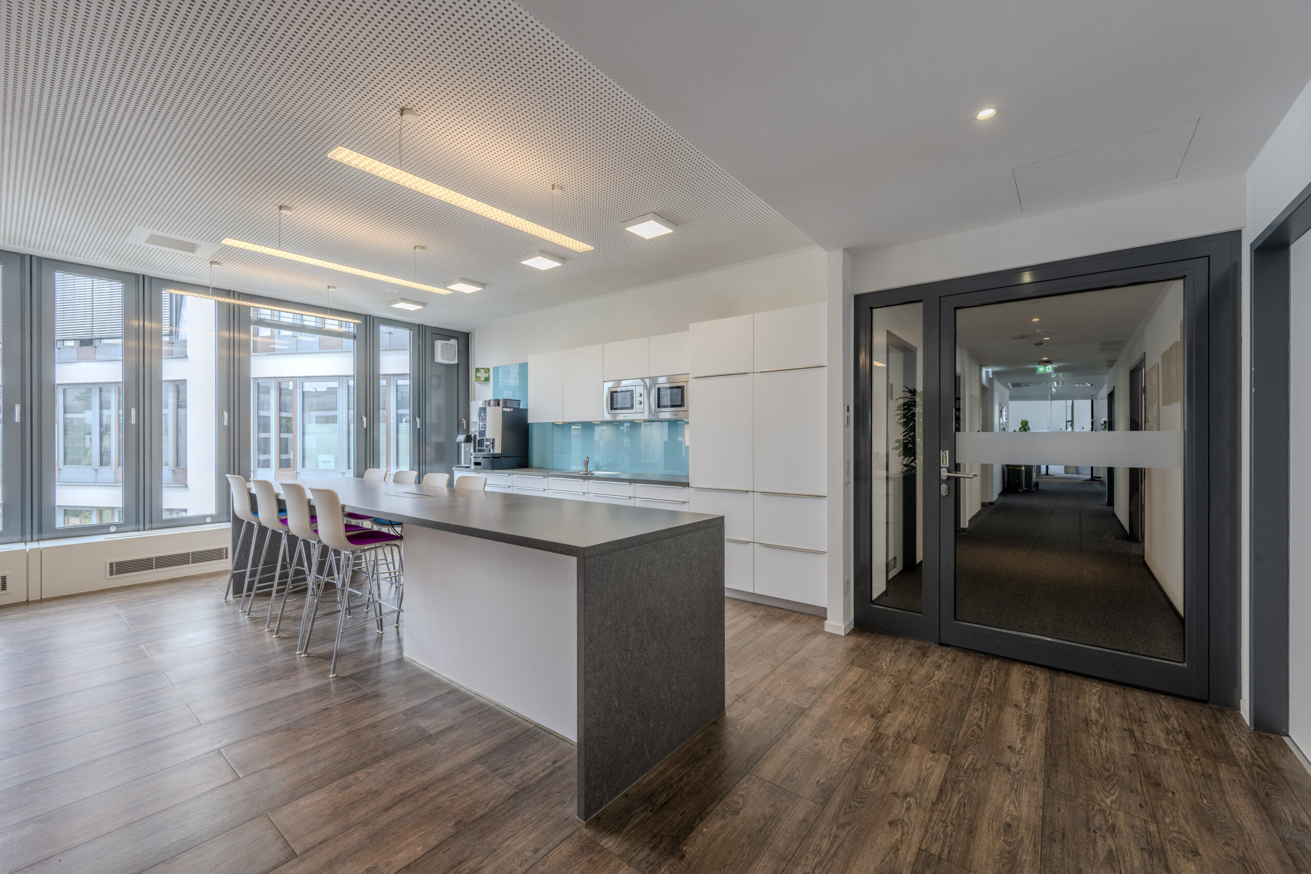 Moderne Büro-Teeküche mit Kücheninsel und Sitzplätzen.